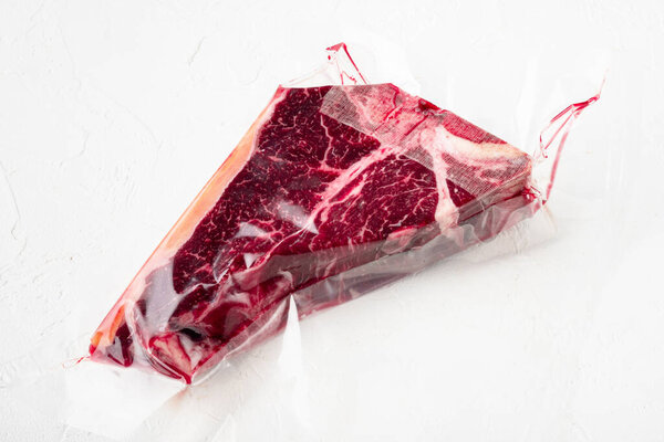 T bone or porterhouse dry aged  steak in vacuum pack  set, on white stone  background
