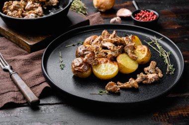 Patatesler ve mantarlar, eski, siyah ahşap masa arkasında.