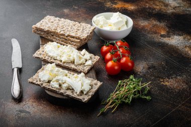 Krem peynir setiyle kepekli çavdar ekmeği, eski koyu kırsal masa arka planında.