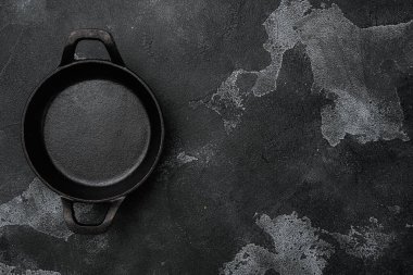 Metin veya yiyecek için kopyalama alanı olan demir kızartma tavası seti, üst görünüm düz, siyah taş masa arkaplanı üzerine