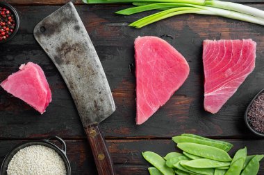 Çiğ susamlı ton balığı bifteği seti, ve eski kasap bıçağı, eski siyah ahşap masa arka planı, üst düz manzara