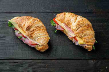 Jambon seti olan kruvasan, siyah ahşap masa arkaplanı, metin için kopyalama alanı