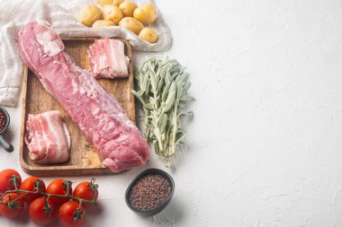 Adaçayı soslu çiğ domuz filetosu, ahşap tepside, beyaz taş zemin üzerinde, metin alanı ve boşluğu ile