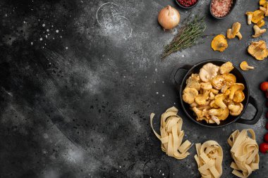Chanterelle mantarı içerikli çiğ tagliatelle, siyah rustik masa arkaplanı üzerinde, üst görünüm düz, metin alanı için kopyalama alanı