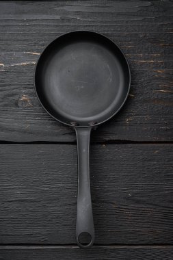 Metin veya yiyecek için kopyalama alanı olan demir kızartma tavası seti, üst görünüm düz, siyah ahşap masa arkaplanı