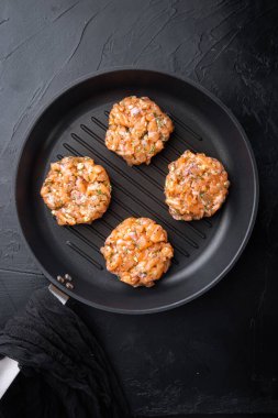 Çiğ balık köfteleri, somon filetosu ve limon otu, siyah desenli arka planda, düz yerde.