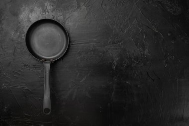 Metin veya yiyecek için kopyalama alanı olan demir kızartma tavası seti, üst görünüm düz, siyah taş masa arkaplanı üzerine