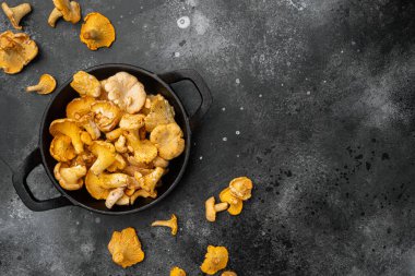 Taze chanterelle mantarları seti, dökme demir kızartma tavasında, siyah taş masa zemininde, üst görünüm düz, metin alanı için kopyalama alanı