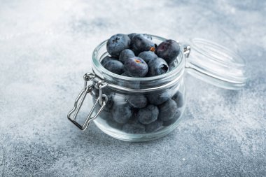 Cam kavanozda olgun yabanmersini, dokulu arka planda..