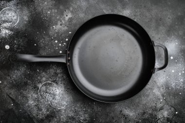 Metin ya da yiyecek için kopyalama alanı ya da yiyecek alanı olan eski model demir tava seti, en üstteki görünüm düz, siyah taş masa arkaplanı üzerinde