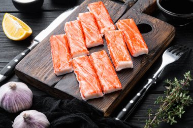 Yengeç köfteleri, deniz ürünleri, balık kıyması, mavi yüzme yengeci seti, tahta kesme tahtası, siyah ahşap masa arkaplanı.