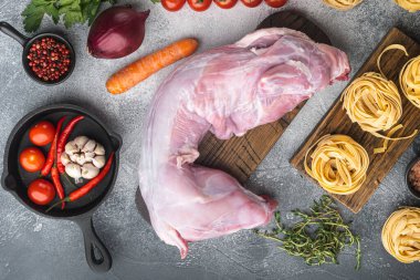 Çiğ tavşan taze sebzeli ve tavşan yahnisi için makarna seti, gri taş arka planda, üst görünüm düz yatıyordu