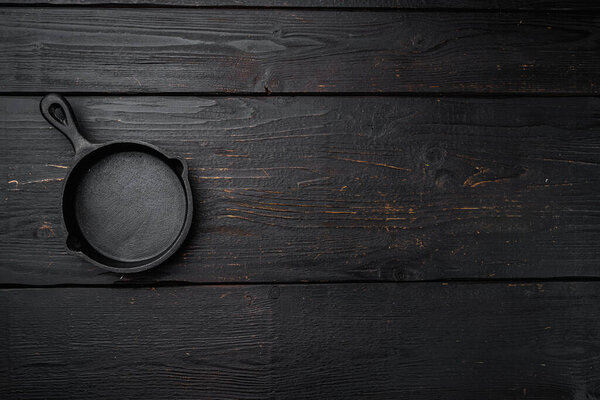 Винтажный чугунный набор сковороды с копировальным местом для текста или еды с копировальным местом для текста или еды, плоский вид сверху, на черном деревянном фоне стола