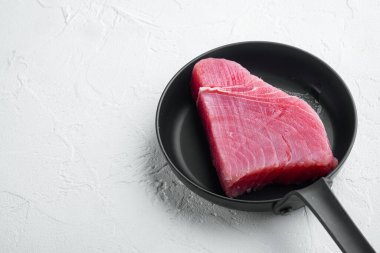 Taze çiğ ton balığı bifteği seti, kızgın demir tavada, beyaz taş arka planda, kopyalanacak yeri ve metin için yeri var.