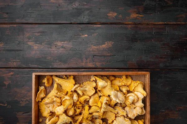 Cantharellus cibarius, commonly known as the chanterelle set, in wooden box container, on old dark  wooden table background, top view flat lay, with copy space for text
