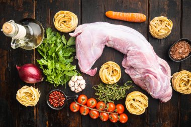 Çiğ taze tüm tavşan yahni seti için kesilmiş, eski siyah ahşap masa arka planı, üst düz yatıyordu