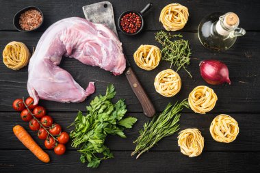 Tavşan güveci tagliatelle malzemeleri seti, siyah ahşap masa arkaplanı, üst görünüm düz yatıyordu