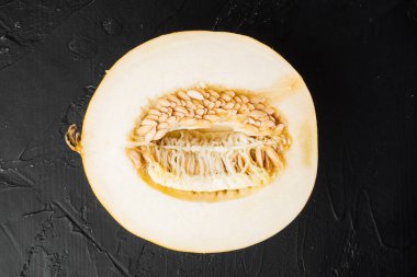 Şeker kavunu ikiye bölünmüş, siyah taş masa zemininde, üst manzara düz.