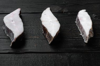 Donmuş çiğ balık bifteği seti, siyah ahşap masa zemininde, metin için kopyalama alanı var.