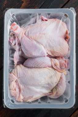 Tüm çiğ tavuk eti paketi, eski ahşap masada, üst tarafta.