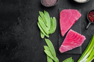 Çiğ susamlı ton balığı bifteği seti, taş tahtada, siyah taş zemin üzerinde, üst görünüm düz, metin için metin alanı ve boşluğu var.