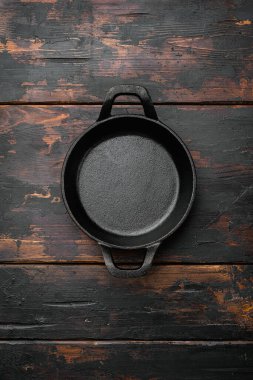 Metin veya yemek için kopyalama alanı olan siyah pişirme tenceresi seti, üst görünüm düz, eski koyu ahşap masa arkaplanı üzerinde