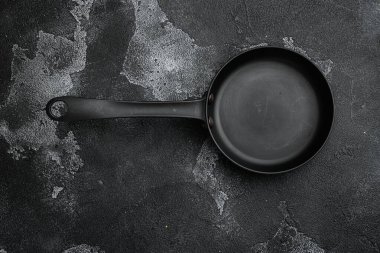 Metin ya da yiyecek için metin ya da yiyecek için kopyalama alanı olan boş kızartma tavası seti, en üstteki düz görünüm, siyah taş masa arkaplanı üzerinde