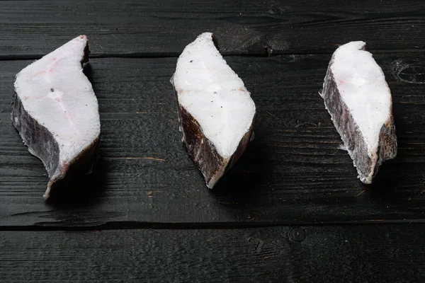 Donmuş çiğ balık bifteği seti, siyah ahşap masa zemininde, metin için kopyalama alanı var.