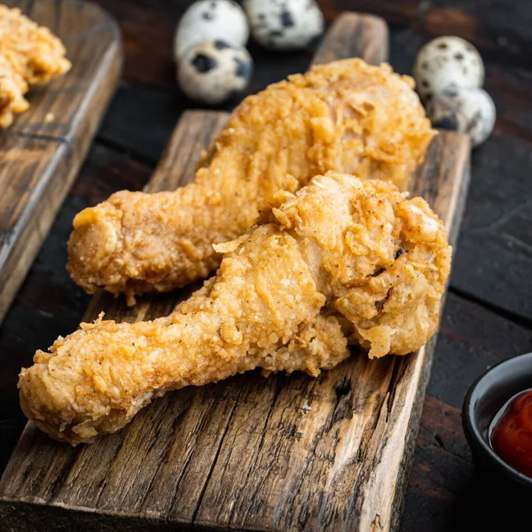 Fried crispy chicken legs, drumstick parts on old dark wooden table.