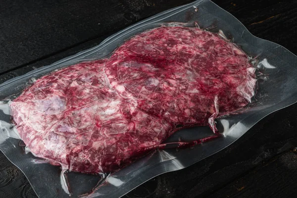Burger meat vacuum sealed ready for sous vide cooking set, on black wooden table background