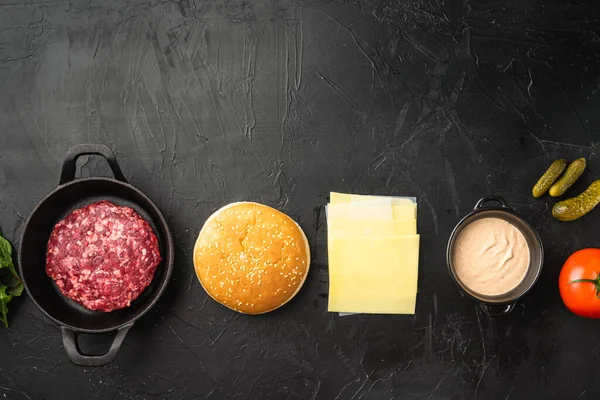 Çiğ öğütülmüş et Burger biftek pirzolası ve ekmekli baharatlar, siyah taş arka planda, düz manzaralı, metin için fotokopi alanı