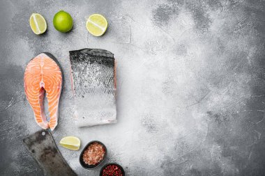 Büyük bir parça çiğ somon balığı seti, gri taş masa arkaplanı, üst görünüm düz, metin için kopyalama alanı ile