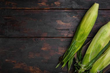 Çuval seti üzerinde çiğ mısır koçanları, eski koyu ahşap masa arkaplanı, üst görünüm düz, metin alanı için kopyalama alanı ile