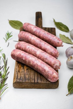 Kızartma seti için çiğ sosis, beyaz taş masa arkasında.