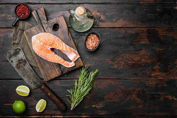 Çiğ somon balığı filetosu taze bitkilerle birlikte, eski koyu ahşap masa zemininde, üst görünümü düz, metin alanı için fotokopi alanı ile