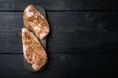 Kırılmış tavuk göğsü malzemesi, siyah ahşap arka planda, düzlük ve metin için yer var.