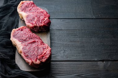 Çiğ büyükelçi bifteği, siyah ahşap arka planda, metin için fotokopi alanı