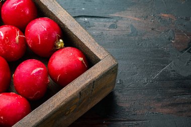 Yaz, kırmızı turp hasat etti. Ahşap kutuda organik sebzeler yetişiyor. Eski, siyah ahşap masa zemininde. Kopyalama alanı ve metin için yeri var.
