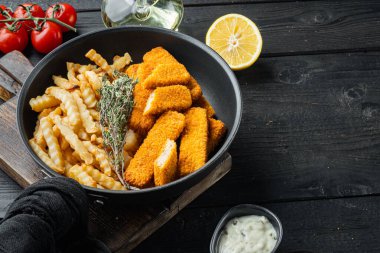 Patates kızartmalı balık kroket kızartma, kızartma demir tavada, siyah ahşap masa zemininde, kopyalanacak yeri ve metin için yeri var.
