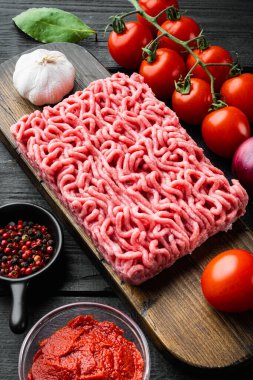 Geleneksel İtalyan domates sosu bolonez malzemeli, kıymalı domates ve otlu, ahşap kesim tahtasında, siyah ahşap masa arkasında.