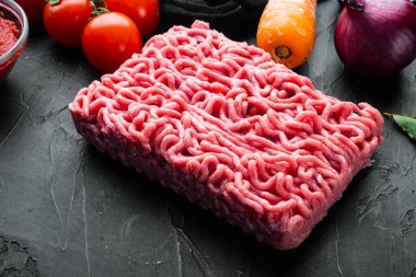 Bolonez sosu malzemelerini hazırlıyorum, kıyma, domates, bitki seti, siyah taş arka planda.