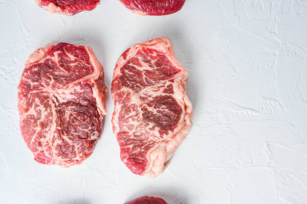 Raw top blade steak. Organic beef. White textured background. Top view with space for text