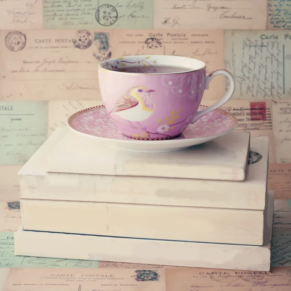 Cup of tea on books and letters on wall — Stock Photo, Image