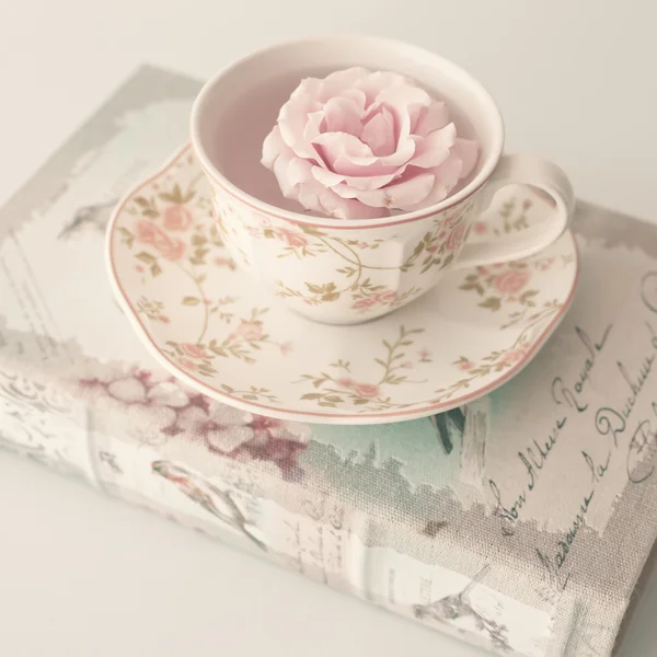 Růže v šálku čaje na knihy — Stock fotografie