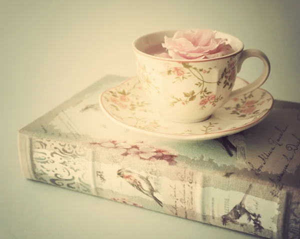 Růže v šálku čaje na knihy — Stock fotografie