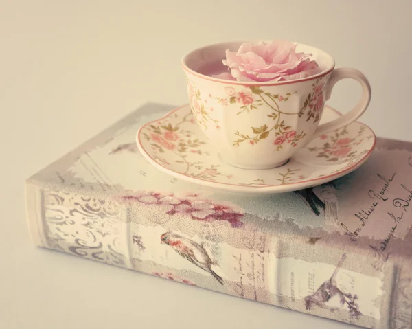 Rose in Tasse Tee auf dem Buch — Stockfoto