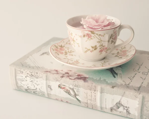 Rosa en taza de té en el libro — Foto de Stock