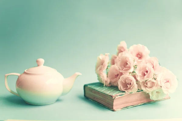 Roses over vintage book and teapot — Stock Photo, Image