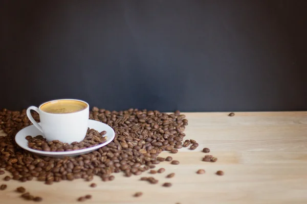 Kaffeetasse und Bohnen über Holz — Stockfoto