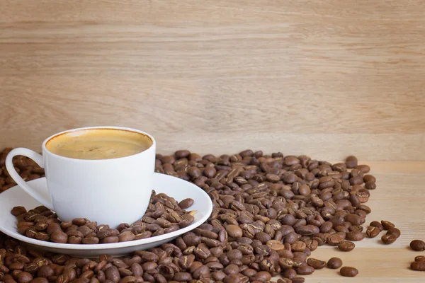 Kaffeetasse und Bohnen über Holz — Stockfoto